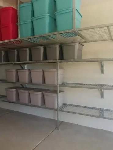 A garage reset with wall shelving, overhead racks, and matching bins.