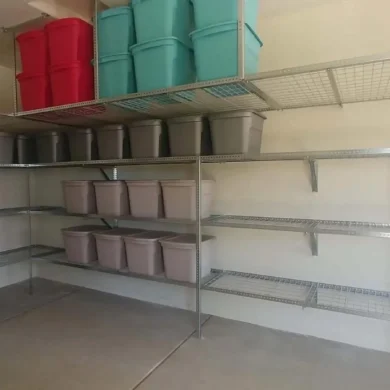 A garage reset with wall shelving, overhead racks, and matching bins.